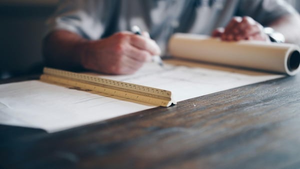 Mains annotant un plan sur un bureau